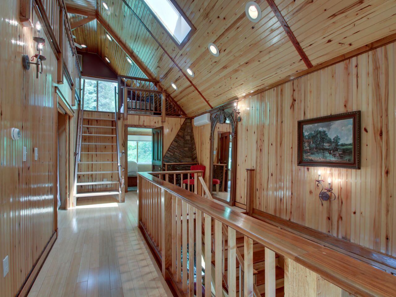 A wooden interior with a staircase leading to an upper level, a wooden railing, and a framed picture on the wall.