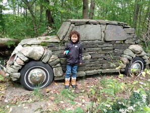 A child standing next to a stone structure resembling a vehicle.