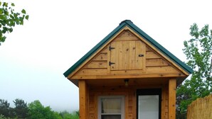Una pequeña cabaña de madera con una mesa de picnic y bancos al frente.