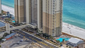 A high-rise hotel with a beach view, a swimming pool, and a parking lot.