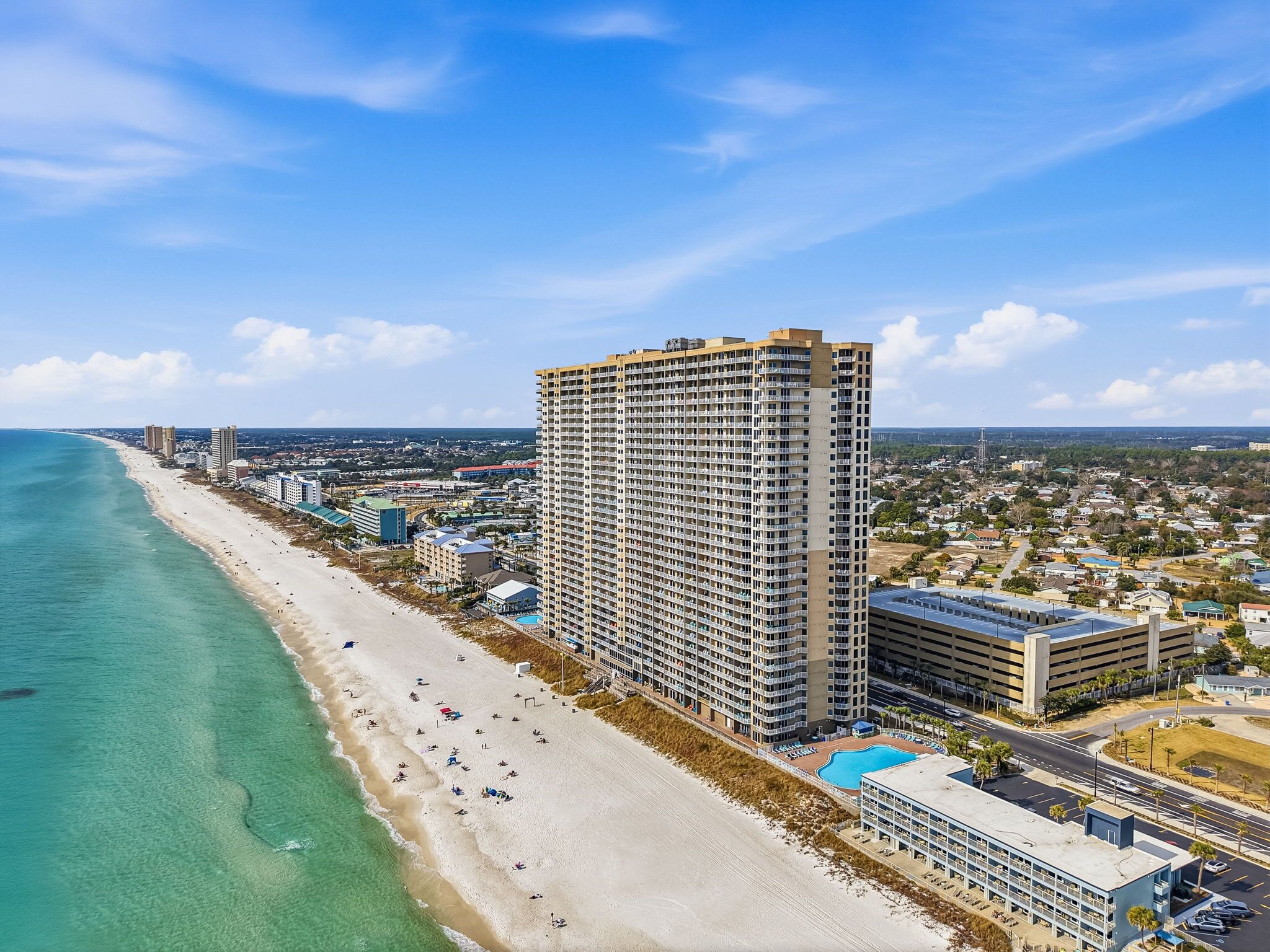 A high-rise hotel with a beach view, multiple floors, and a swimming pool.