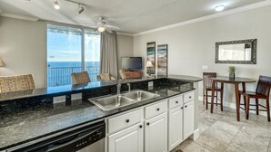 A modern kitchen with a large island, built-in dishwasher, and a dining area with a table and chairs.