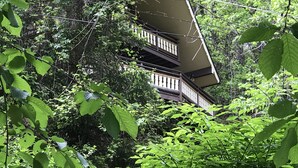 Un edificio de varios pisos con balcones, rodeado de abundante vegetación.