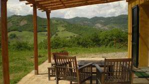 Une pergola en bois avec une table et des chaises, donnant sur un paysage verdoyant.