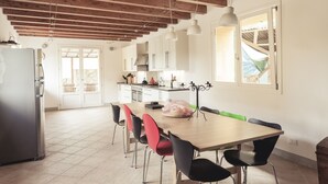 Une cuisine spacieuse avec un plafond en bois, une table à manger avec des chaises et un réfrigérateur.
