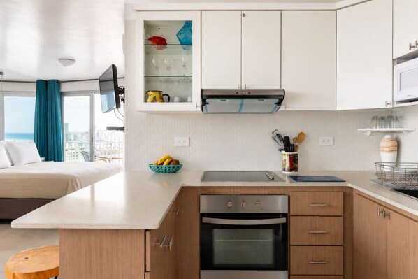 A modern kitchen with a built-in oven, a microwave, and a glass-fronted cabinet above the stove.