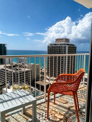A balcony with a view of the ocean and a Marriott hotel in the background.