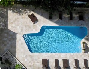 An aerial view of a swimming pool with a sun lounger and several lounge chairs.