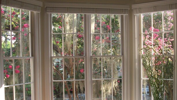 Una habitación con un amplio ventanal que da a un jardín con flores rosadas.