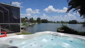 A hot tub with a clear view of a lake and surrounding greenery. - Beautiful Villa Lake View Heated Pool, Salt💧Spa & Kayak’s🐠 Simply Wonderful! (Cape Coral)