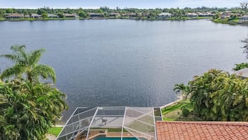 Enjoy unobstructed lake views from the pool with lush greenery and palm trees surrounding the serene lakeside property.