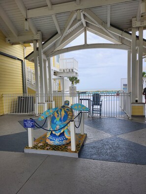 A covered area with a white railing, a sign indicating pool rules, and a colorful turtle sculpture.