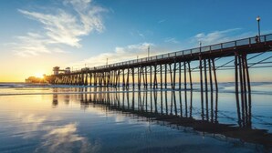 A pier extending into calm waters with a clear sky and a sunset. - Private Enchanted Garden (Oceanside)