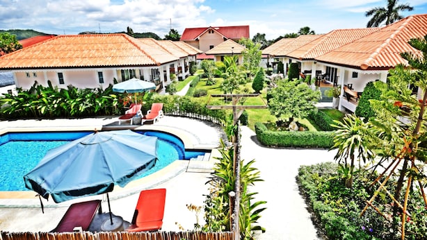Et resort med swimmingpool, liggestole og en velplejet have.