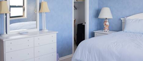 A bedroom with a bed, a dresser, two lamps, and a mirror.