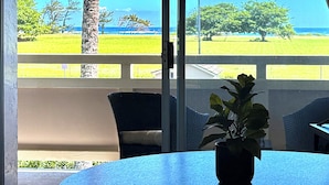 A room with a view of the ocean, a palm tree, and a potted plant on a table. - Deluxe 1 Bedroom Ocean View Condo 5 minute walk to beach, hot tub and pools  (Kapaa)