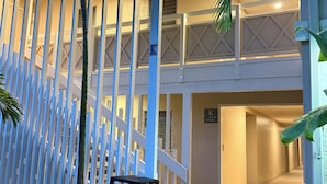 A two-story building with a white exterior and a balcony on the upper floor. - Deluxe 1 Bedroom Ocean View Condo 5 minute walk to beach, hot tub and pools  (Kapaa)