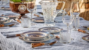 A table set with dinnerware, glasses, and a decorative bowl. - LaQuerciaEstate -Quintessential Italian Experience (Impruneta)