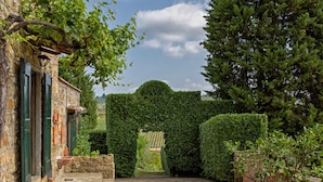 A stone building with a brick pathway leading to a green archway. - LaQuerciaEstate -Quintessential Italian Experience (Impruneta)