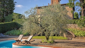 A pool with two lounge chairs, a stone building, and a tree in the background. - LaQuerciaEstate -Quintessential Italian Experience (Impruneta)