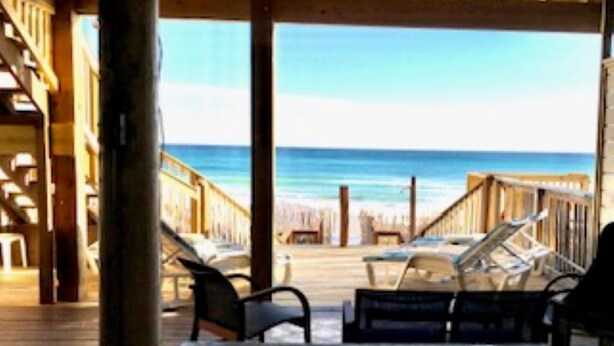 A wooden deck with lounge chairs facing the ocean.
