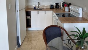 A modern kitchen with white cabinets, a microwave, a coffee maker, and a sink.