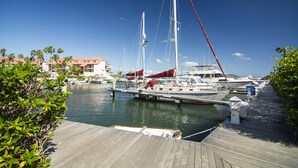 A marina with several boats docked, a wooden dock, and a building in the background.