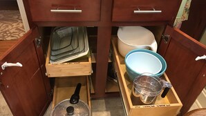 A kitchen with wooden cabinets, a pressure cooker, a kettle, and a measuring cup in a drawer. - 5* Cutie Has It All! Just Bring Family & Friends! (Nashville)