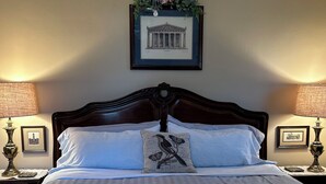 A neatly made bed with a striped bedspread, a decorative pillow with a bird and butterflies, and a framed picture of a classical building on the wall. - 5* Cutie Has It All! Just Bring Family & Friends! (Nashville)