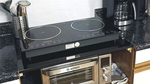 Een kleine keuken met een ingebouwde kookplaat, een koffiezetapparaat en een magnetron.