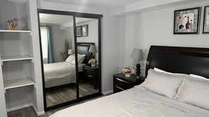 Een hotelkamer met een bed, nachtkastje, spiegel en kledingkast.