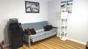 Een compacte leefruimte met een bank, een klein kitchenette en een boekenkast.