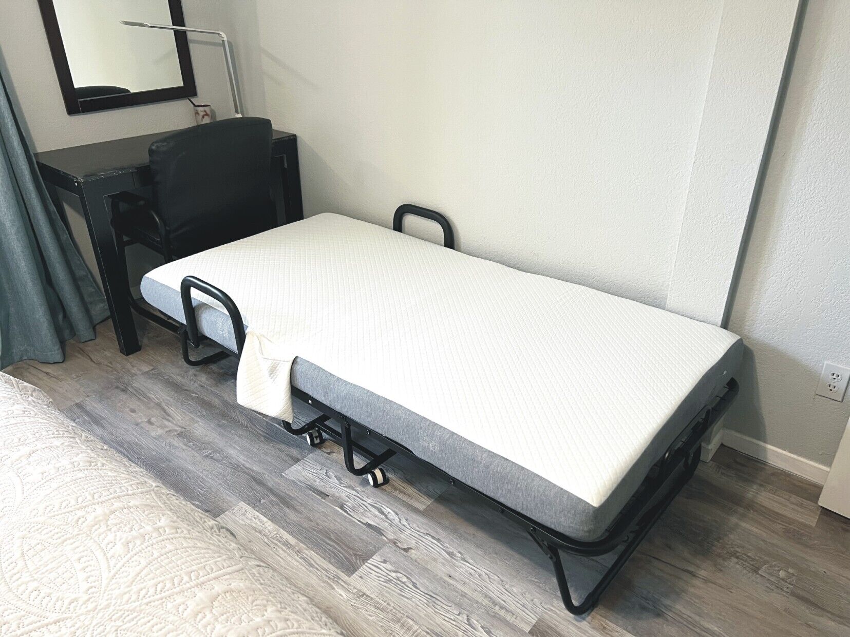 A compact room with a foldable bed, a desk, and a chair.