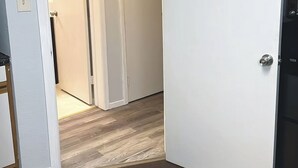 Een gang met een houten vloer, een witte deur en een zichtbaar deurklink.