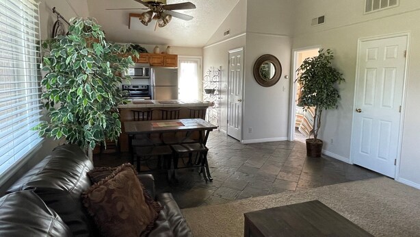 A spacious living room with a leather couch, a wooden coffee table, and a dining area with a kitchen in the background. - Great Deck for Spectacular Sunrises in Sports Village (St George)