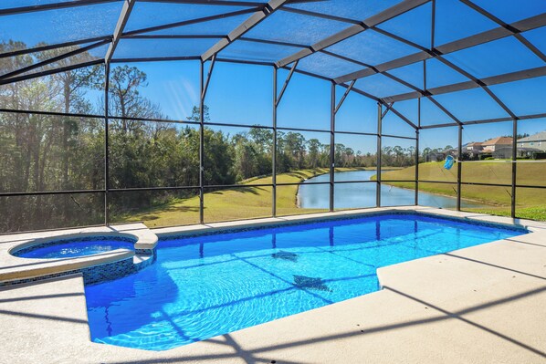 A swimming pool with a clear view of the surrounding landscape, including trees and a distant body of water.