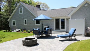 A patio with a stone fire pit, outdoor furniture, and a grill area. - Fabulous 3BR/3BA vacation house in Cotuit that sleeps 8 and only 1 mile to beach (Cotuit)