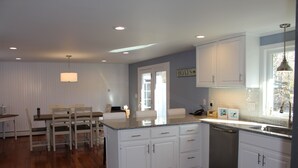 A modern kitchen with white cabinetry, a granite countertop, and a built-in dishwasher. - Fabulous 3BR/3BA vacation house in Cotuit that sleeps 8 and only 1 mile to beach (Cotuit)