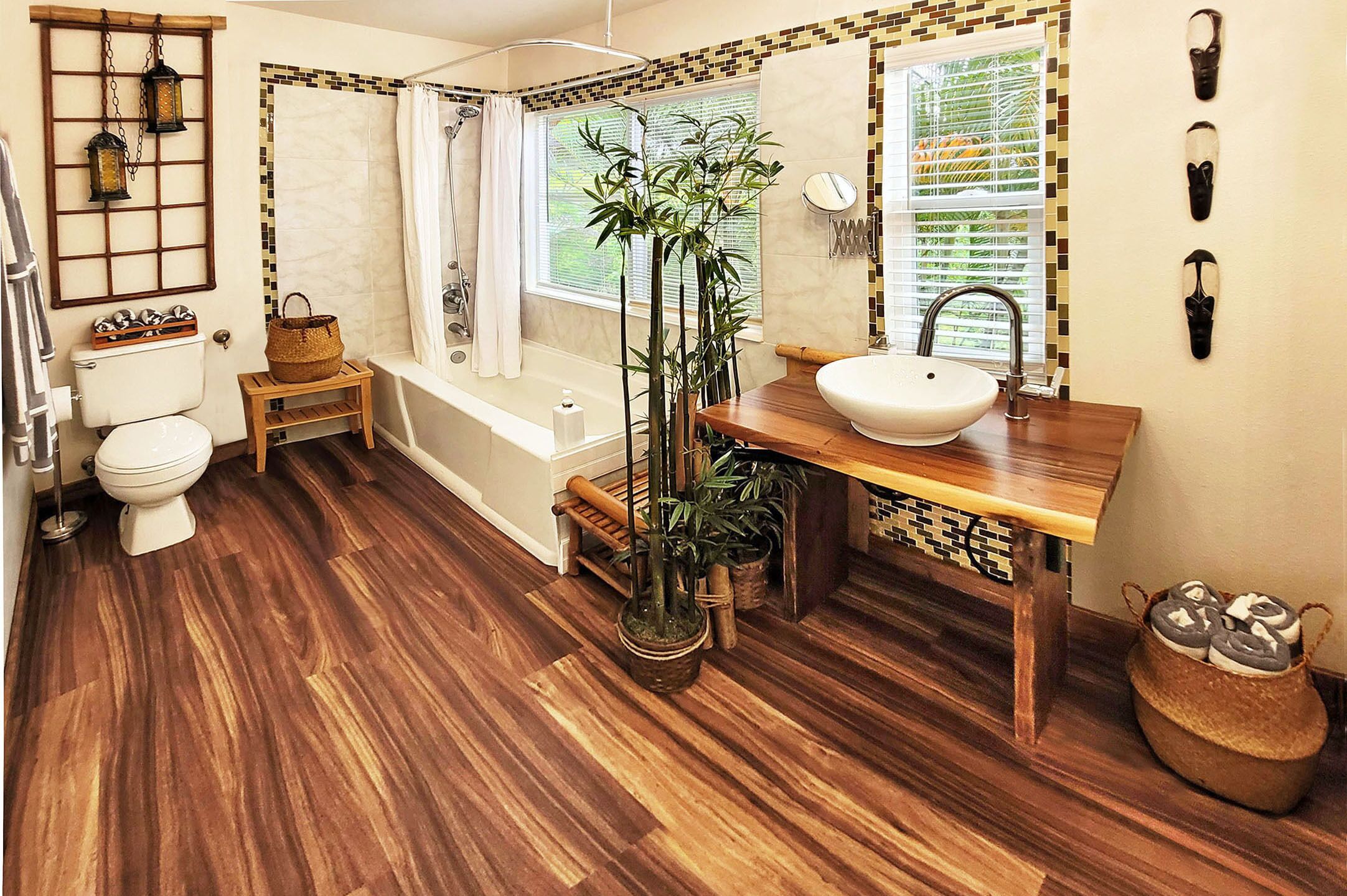 A bathroom with a wooden floor, toilet, bathtub, and sink.