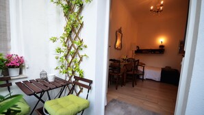 Zona d'estar exterior amb taula i cadires de fusta, una panxa d'amortidor groga i una planta enfiladissa.