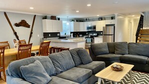 Un soggiorno moderno con un divano modulare grigio, un tavolino in legno e una zona pranzo con sedie in legno.