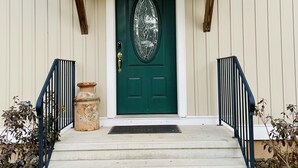 Un edificio con una porta verde, un portico con gradini e un piccolo vaso sui gradini.