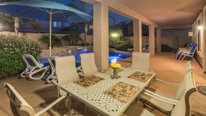 An outdoor patio with a pool, lounge chairs, and a table with a vase of flowers. - SUNLAND VILLA - High End resort with heated pool/spa, few minutes to golf course (Goodyear)