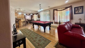 A spacious living room with a pool table, a red leather sofa, and a dining area with wooden furniture. - SUNLAND VILLA - High End resort with heated pool/spa, few minutes to golf course (Goodyear)