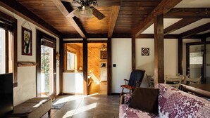 Un amplio salón con techo de madera, un sofá, un televisor y una mesa de comedor.