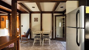 Una cocina con un refrigerador blanco, una mesa de comedor de madera con sillas y una mecedora.