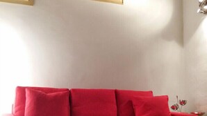 A red sofa in a room with tiled flooring and two paintings on the wall. - Enchanting Florentine Gem: Perfect Location! (florence)