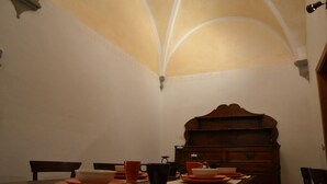 A dining area with a high arched ceiling, a wooden table set with plates and cups, and a vintage-style cabinet in the background. - Enchanting Florentine Gem: Perfect Location! (florence)