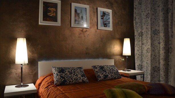 A bedroom with a large bed, two nightstands, a headboard, and three framed pictures on the wall. - Enchanting Florentine Gem: Perfect Location! (florence)
