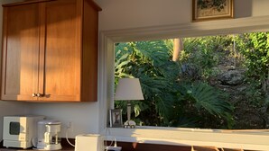 Eine Küche mit Holzausstattung, einer Kaffeemaschine, einem Toaster und einem Fenster mit Blick ins Grüne.